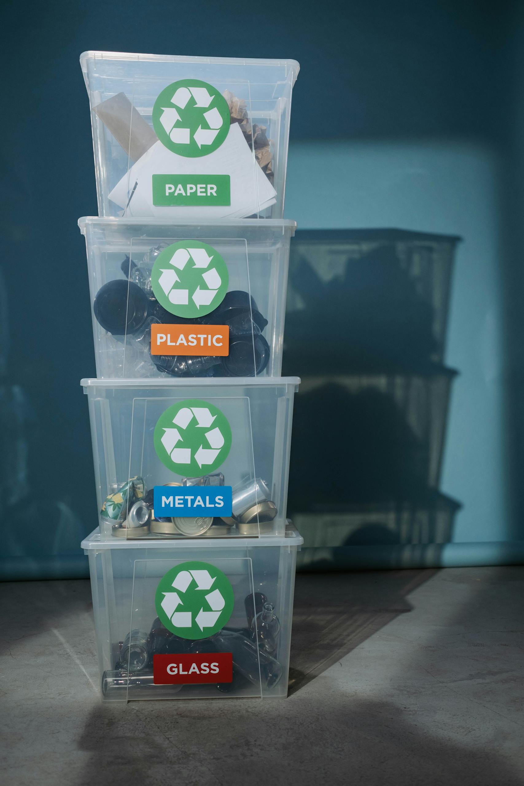 Vertical shot of labeled recycling bins for paper, plastic, metals, and glass.